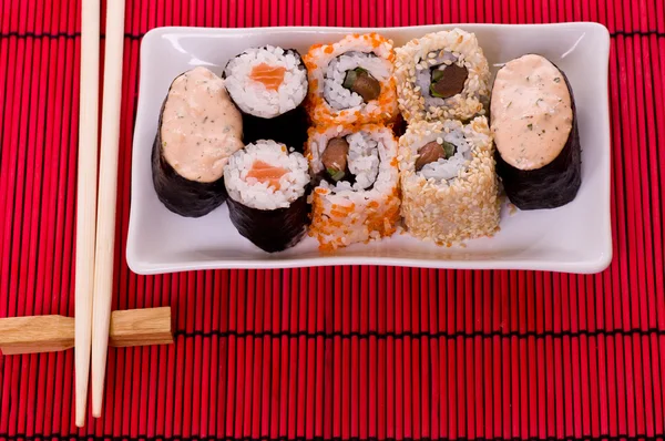 Ensemble de rouleaux de sushi sur la plaque blanche avec des fleurs — Photo