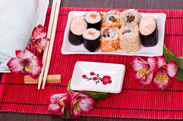 Set di involtini di sushi sul piatto bianco con fiori — Foto Stock