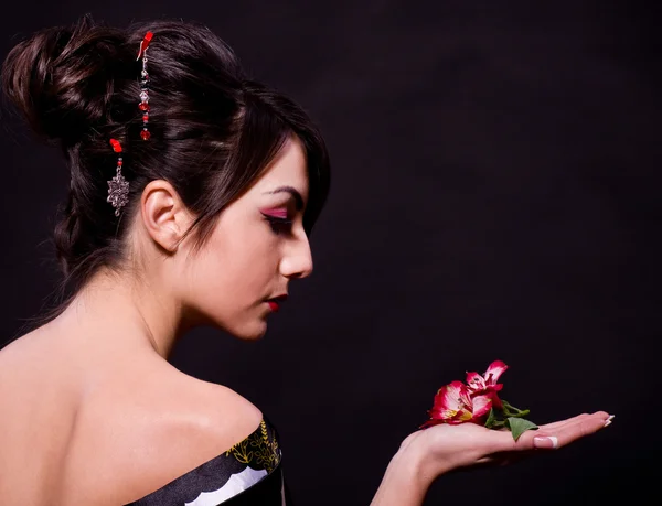 Mulher em traje asiático com flores vermelhas — Fotografia de Stock