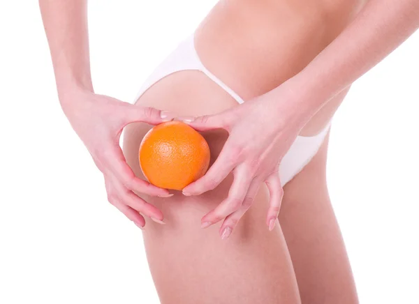 Woman's hands holding an orange and beautiful woman body — Stock Photo, Image