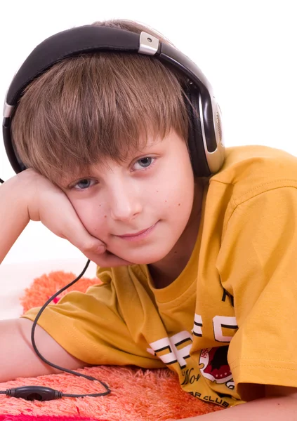 Маленький улыбающийся мальчик слушает музыку в наушниках — стоковое фото