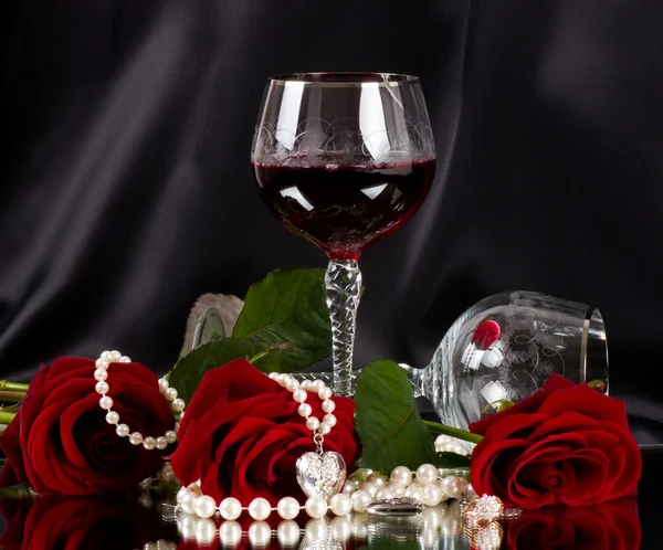 Vidrio de vid rojo con rosas rojas sobre fondo negro —  Fotos de Stock