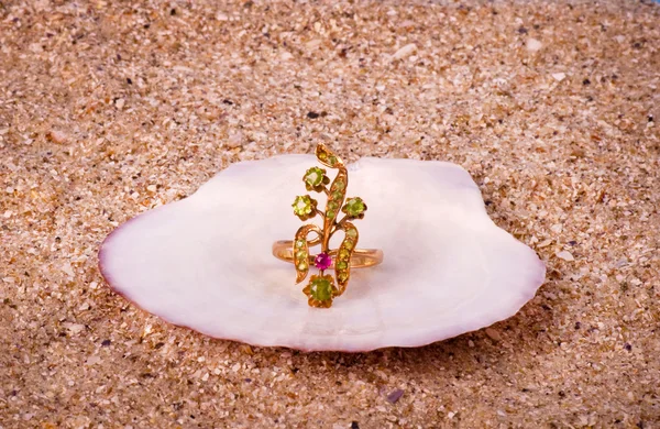 Gouden juwelen in shell op zand achtergrond — Stockfoto