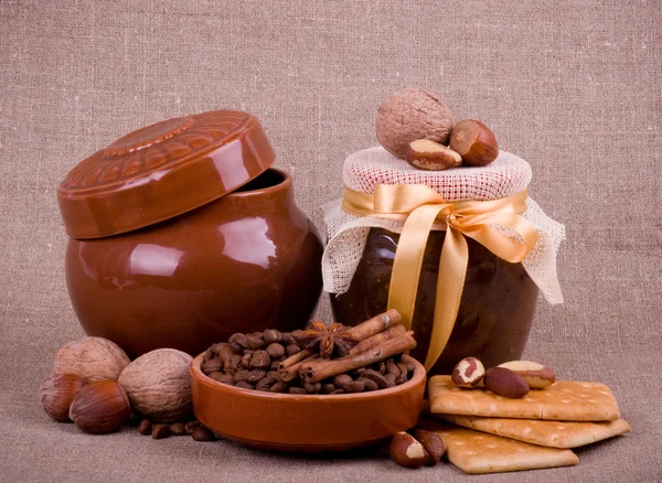 Вкусный джем, кексы, глиняный горшок и орехи на заднем плане — стоковое фото