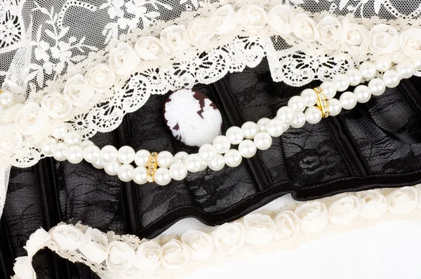 Black lace with form flower, pearls and antique cameo on white background — Stock Photo, Image