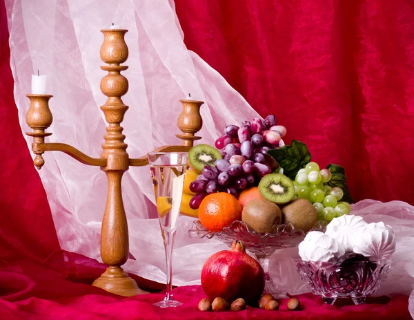 Komposisi indah dengan buah-buahan, lilin dan anggur pada vas di latar belakang merah — Stok Foto