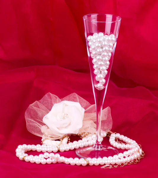 Bílý květ, perlami a korálky na červeném pozadí — Stock fotografie