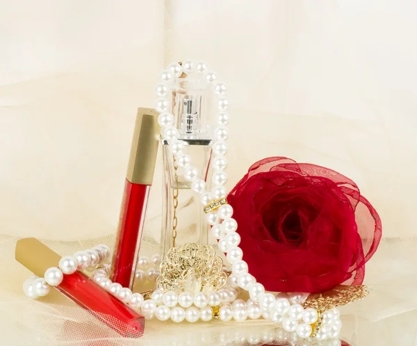 Frascos de perfume, lápiz labial rojo, plumas, rosas y perlas — Foto de Stock