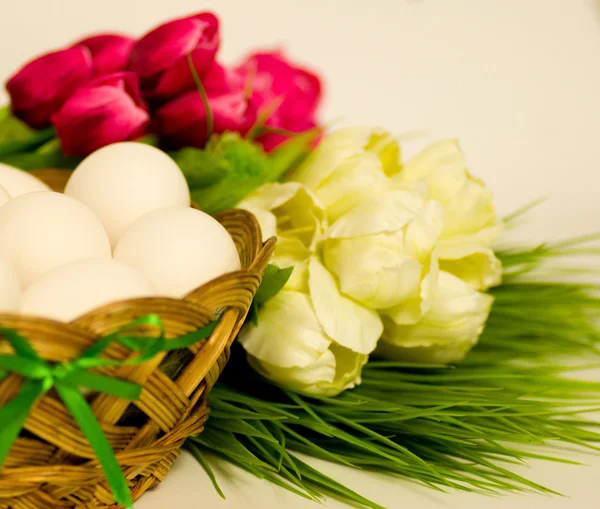 Καλάθι με αυγά του Πάσχα και Ανοιξιάτικα λουλούδια σε άσπρο φόντο — Φωτογραφία Αρχείου