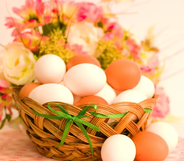 Кошик з великодніми яйцями та весняними квітами на білому тлі — стокове фото