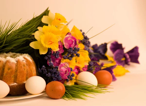 Корзина с пасхальными яйцами и весенними цветами на белом фоне — стоковое фото