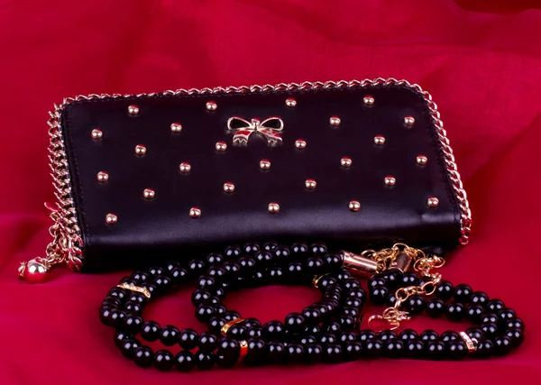 Fashionable handbag and beads on red background. — Stock Photo, Image