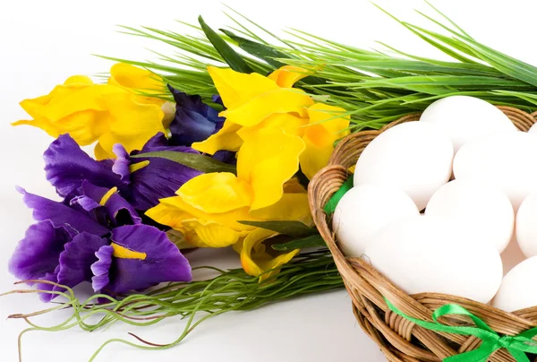 Koš s velikonoční vajíčka a jarní květiny — Stock fotografie
