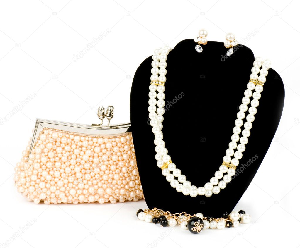 Fashionable handbag and pearl jewelry on white background.