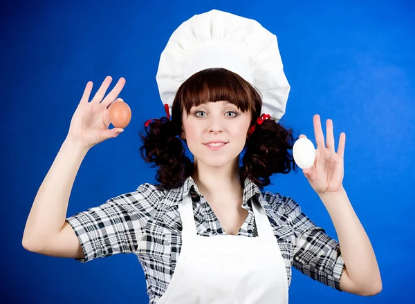 Улыбающаяся счастливая кухарка держит пасхальные яйца — стоковое фото