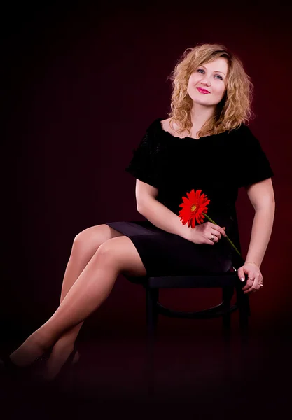 Kvinnan i svart klänning med röd blomma — Stockfoto