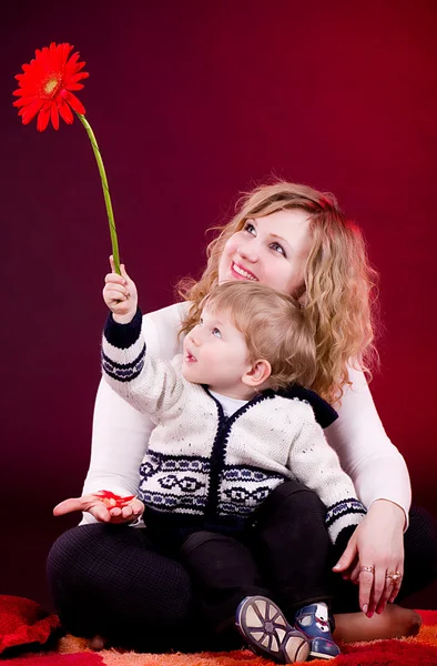 Portré, az anya és a fiatal baby boy piros virággal — Stock Fotó