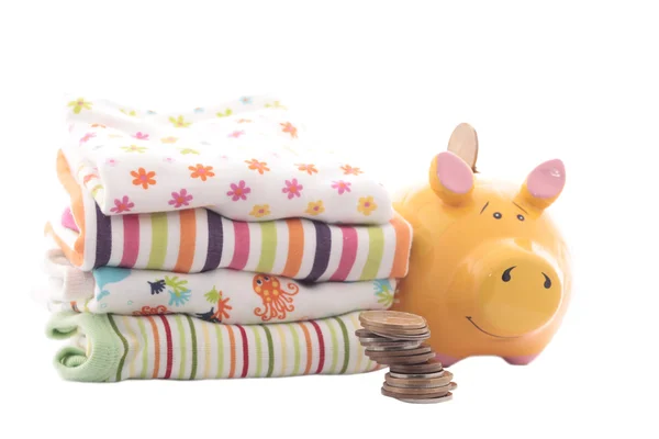 Yellow piggy bank with baby's clothes — Stock Photo, Image