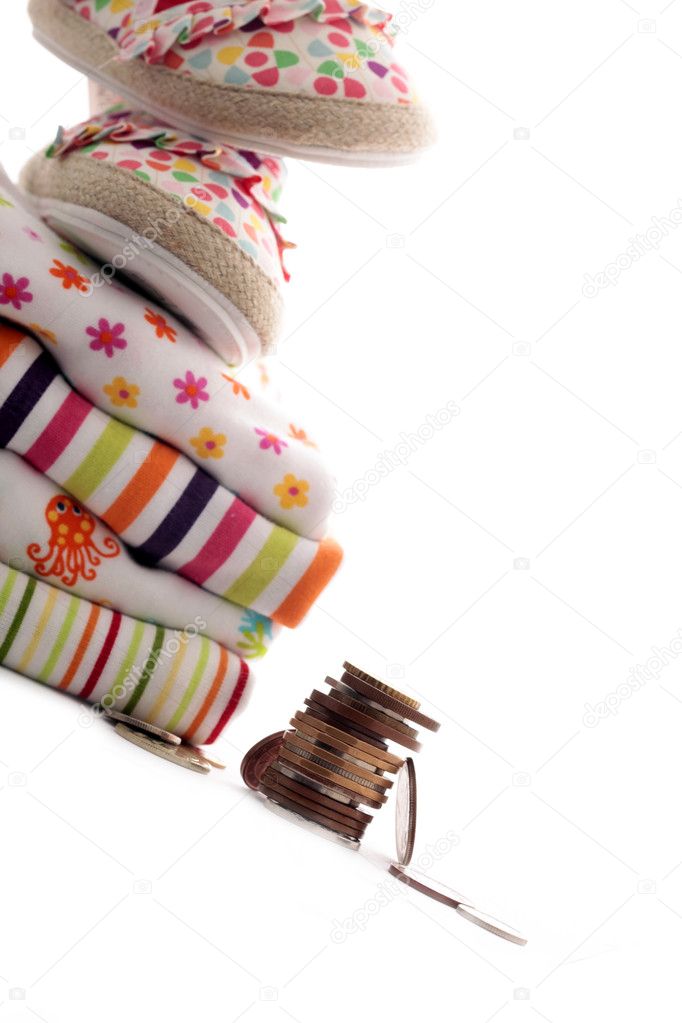 Newborn baby clothes and stack of coins
