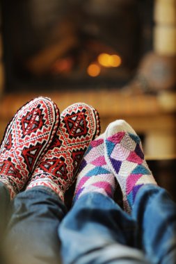 Young romantic couple sitting on sofa in front of fireplace at h clipart