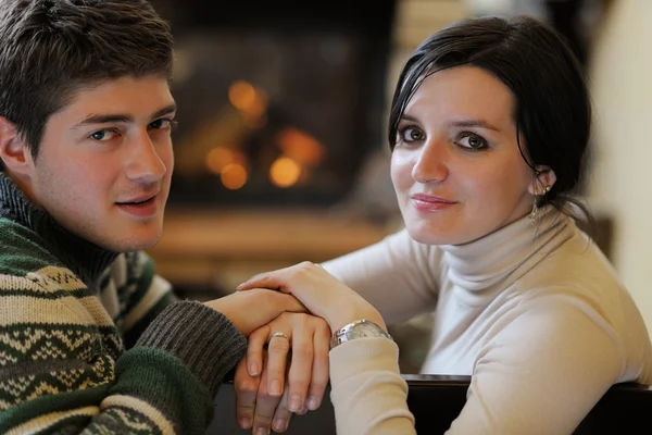 Молодая романтическая пара расслабиться на диване перед камином в доме — стоковое фото