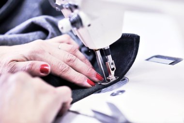 Hands of Seamstress Using Sewing Machine clipart