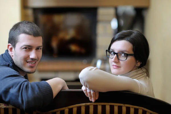 Joven pareja romántica sentada y relajada frente a la chimenea en casa — Foto de Stock