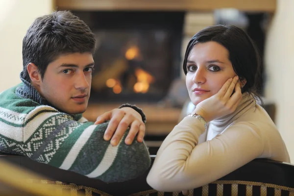Joven pareja romántica sentada y relajada frente a la chimenea en casa — Foto de Stock