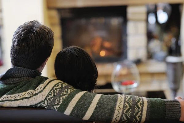 Young romantic couple sitting and relaxing in front of fireplace at home — Stock Photo, Image