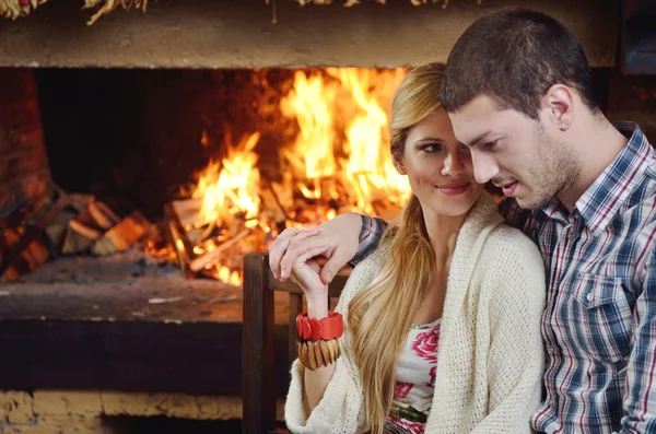 Joven pareja romántica sentada y relajada frente a la chimenea en casa —  Fotos de Stock