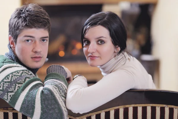 Joven pareja romántica sentada y relajada frente a la chimenea en casa — Foto de Stock