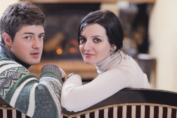 浪漫的年轻夫妇坐和舒舒服服坐着在家里的壁炉 — 图库照片
