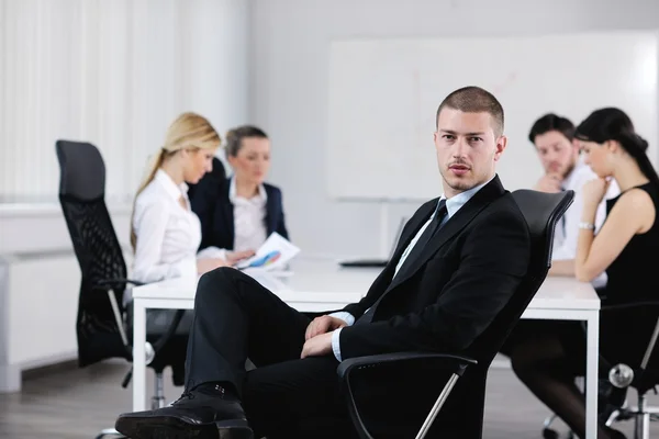 Portrait of a handsome young business man with colleagues in background — Stock Photo, Image