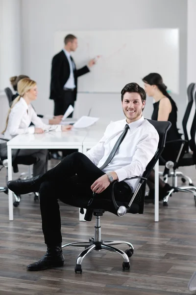 Portrait of a handsome young business man with colleagues in background — Stock Photo, Image