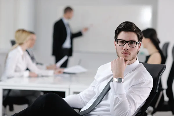 Portrait of a handsome young business man with colleagues in background — Stock Photo, Image