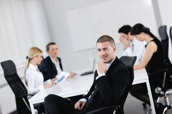 Handsome young business man with colleagues in background — Stock Photo, Image