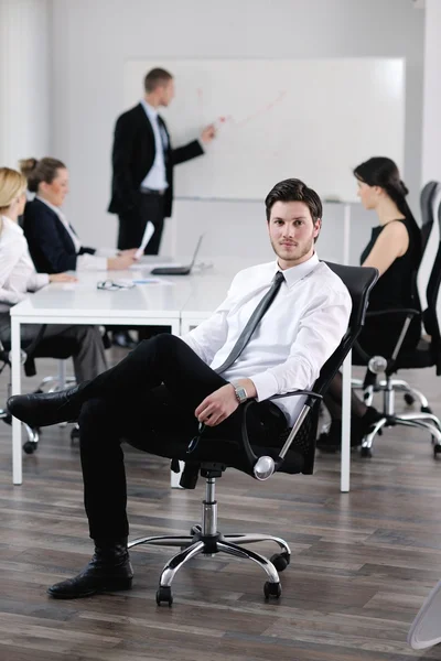 Knappe jonge zakenman met collega's op achtergrond — Stockfoto