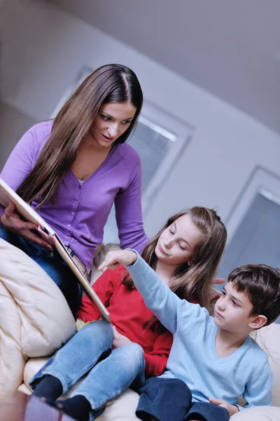 Joven mamá jugar con sus hijos en casa y leer libro —  Fotos de Stock
