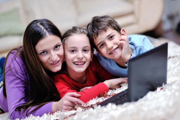 Jovem mãe brincar com seus filhos em casa e ler livro — Fotografia de Stock