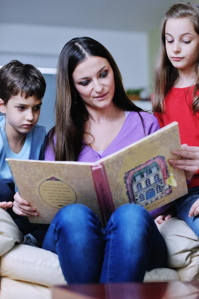 Mladá maminka hrát se svými dětmi doma a čtení knih — Stock fotografie