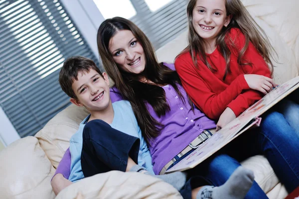 Giovane mamma giocare con i loro figli a casa e leggere il libro — Foto Stock