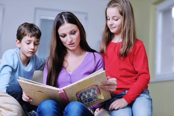 Genç anne oyun onların evde çocuklar ve kitap okumak — Stok fotoğraf