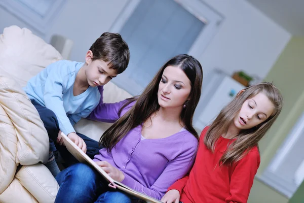 Jonge moeder spelen met hun kinderen thuis en leesboek — Stockfoto