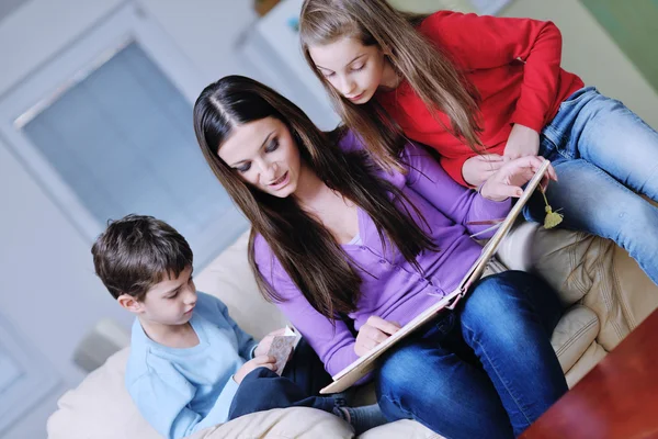 Mladá maminka hrát se svými dětmi doma a čtení knih — Stock fotografie