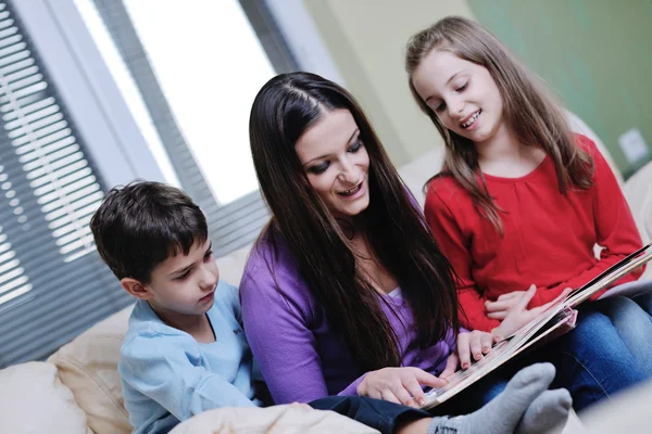 Jonge moeder spelen met hun kinderen thuis en leesboek — Stockfoto