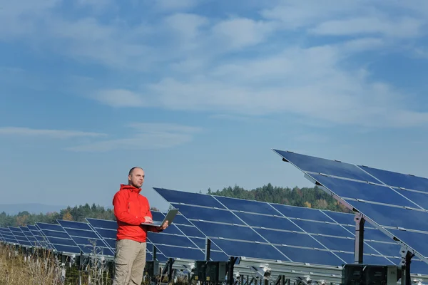 Ingeniero que usa el ordenador portátil en el campo de la planta de paneles solares — Foto de Stock