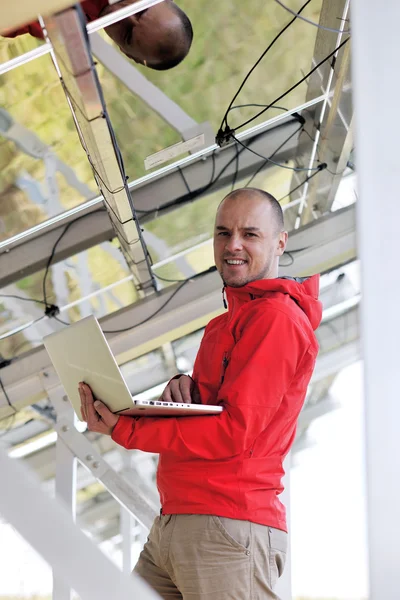 Μηχανικός που χρησιμοποιεί το lap-top στο πεδίο εγκαταστάσεων ηλιακών πινάκων — Φωτογραφία Αρχείου