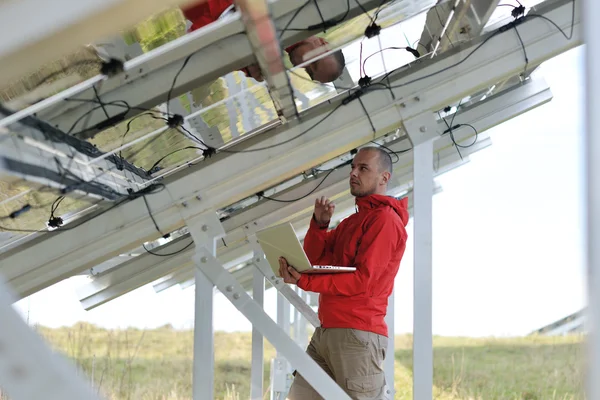 Ingegnere che utilizza il computer portatile al campo dell'impianto dei pannelli solari — Foto Stock