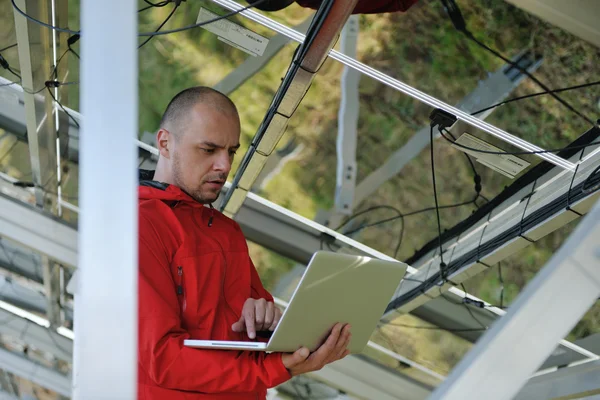 Ingegnere che utilizza il computer portatile al campo dell'impianto dei pannelli solari — Foto Stock