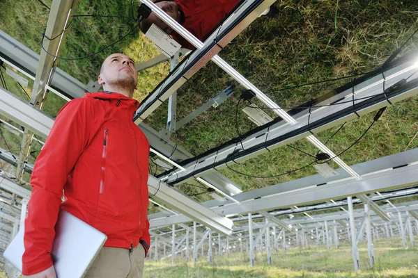 Engenheiro usando laptop no campo de planta de painéis solares — Fotografia de Stock